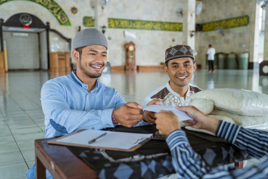 Muslim man giving zakat charity for eid mubarak at the mosque